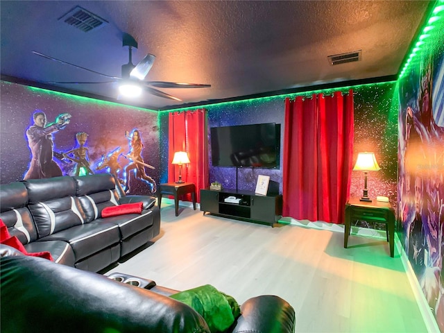 home theater room with ceiling fan, hardwood / wood-style flooring, and a textured ceiling