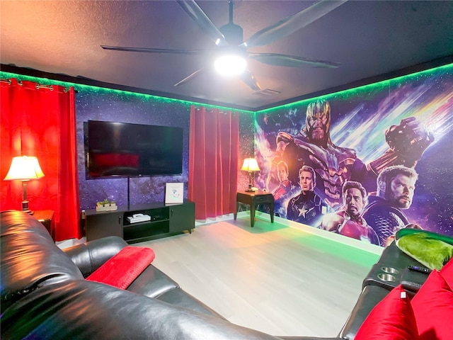 home theater room with ceiling fan, wood-type flooring, and a textured ceiling