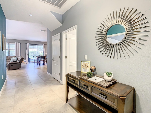 hall featuring vaulted ceiling and light tile patterned floors