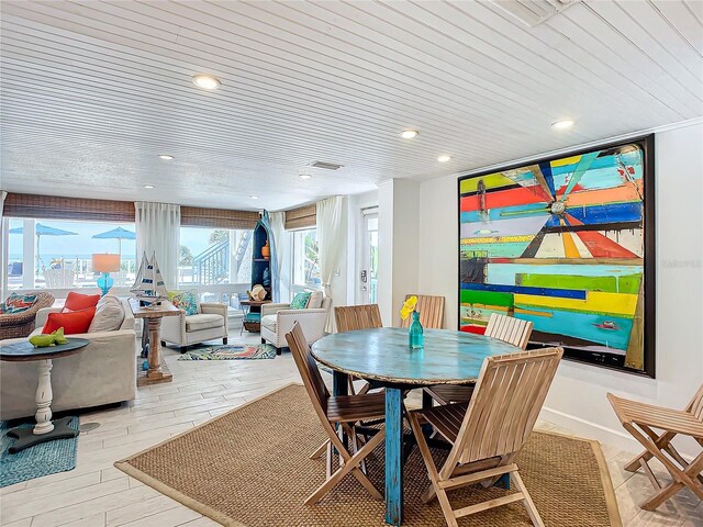 dining space with light wood-type flooring and wooden ceiling