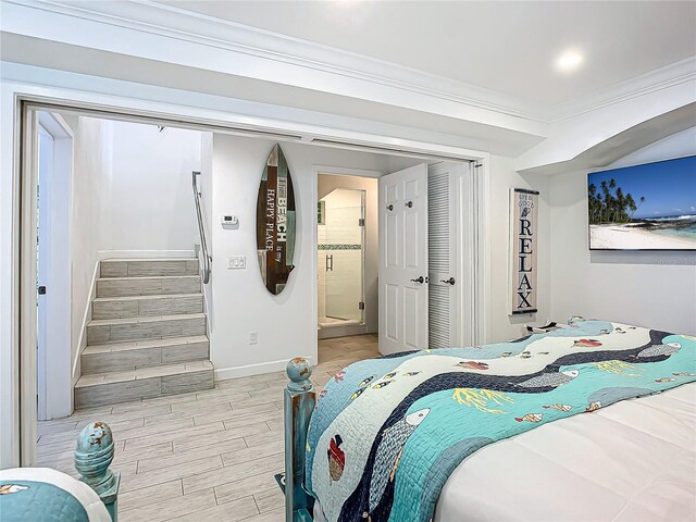 bedroom featuring light wood-type flooring, ornamental molding, and ensuite bath