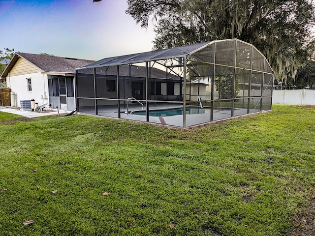 back of house with a fenced in pool, a yard, central air condition unit, and glass enclosure