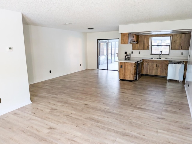 kitchen with light hardwood / wood-style floors, a textured ceiling, stainless steel appliances, and sink