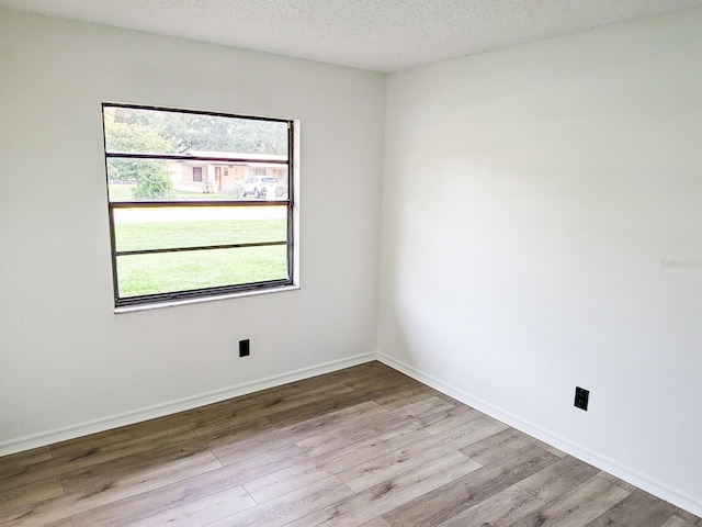 unfurnished room featuring light hardwood / wood-style floors and a textured ceiling