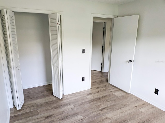 unfurnished bedroom with light wood-type flooring and a closet