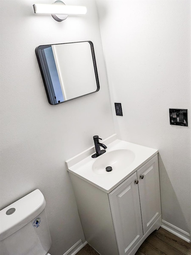 bathroom with wood-type flooring, vanity, and toilet