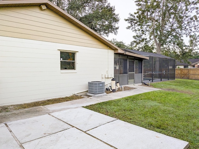 rear view of property featuring a lawn, cooling unit, a sunroom, and a patio area