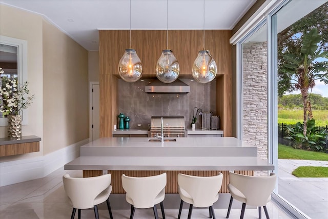 interior space featuring stainless steel stove, sink, wall chimney range hood, and a kitchen breakfast bar