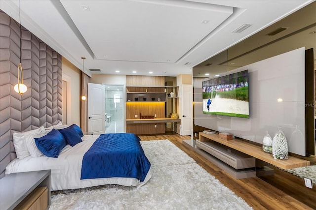 bedroom featuring dark hardwood / wood-style flooring, a raised ceiling, and connected bathroom