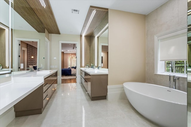 bathroom featuring vanity, a bathing tub, tile walls, and tile patterned floors