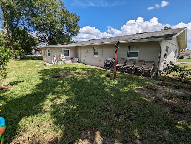 rear view of property with a lawn and central air condition unit