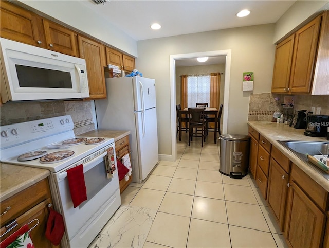 kitchen featuring white appliances, backsplash, and sink