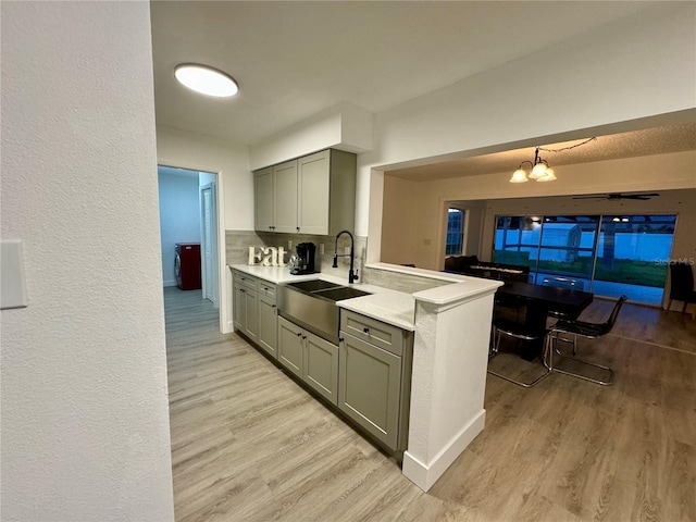 kitchen with pendant lighting, a notable chandelier, light hardwood / wood-style floors, and sink