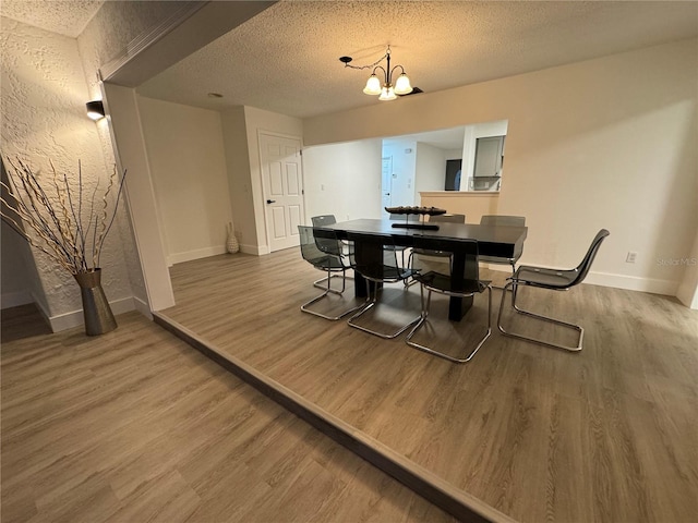 dining room with hardwood / wood-style floors, a notable chandelier, and a textured ceiling