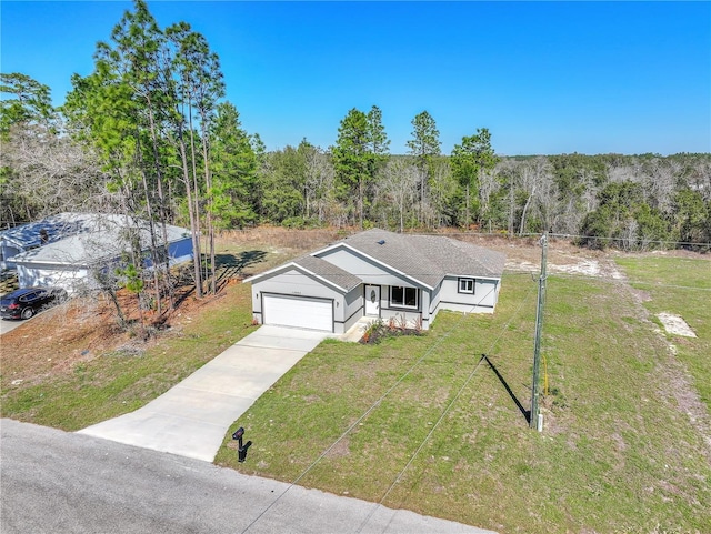 view of front facade featuring a garage, fence, driveway, a front lawn, and a view of trees