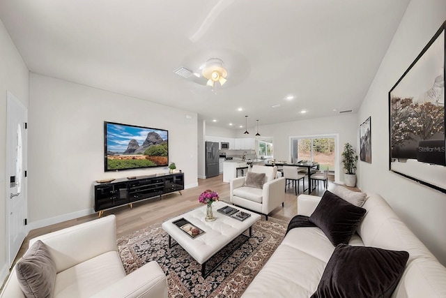 living area featuring light wood-style floors, baseboards, visible vents, and recessed lighting