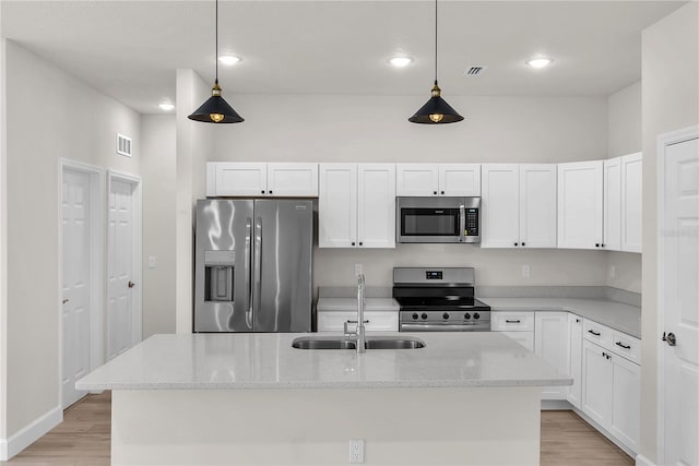 kitchen featuring light wood finished floors, visible vents, white cabinets, stainless steel appliances, and a sink