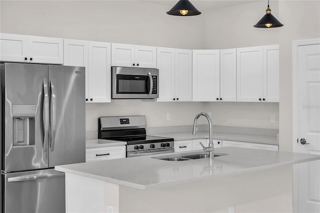 kitchen with appliances with stainless steel finishes, white cabinetry, a sink, and decorative light fixtures