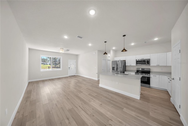 kitchen featuring stainless steel appliances, a sink, visible vents, open floor plan, and light countertops