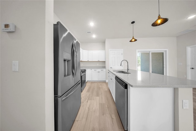 kitchen featuring stainless steel appliances, light countertops, light wood-style floors, white cabinets, and a sink