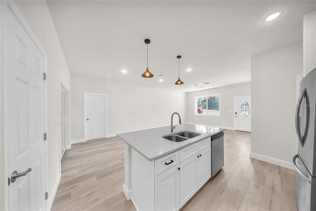 kitchen featuring open floor plan, stainless steel appliances, a sink, and light wood-style floors