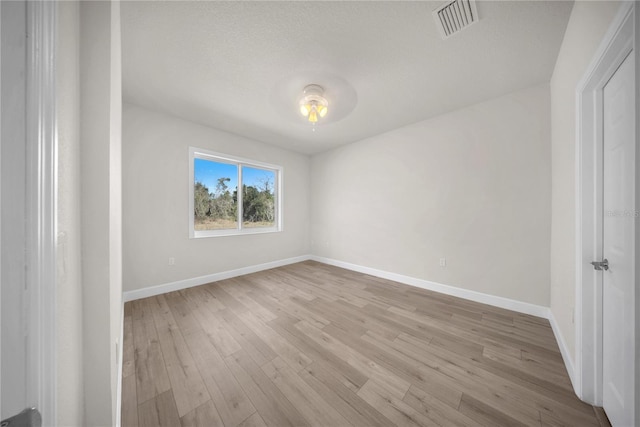 empty room featuring light wood-type flooring, baseboards, and visible vents