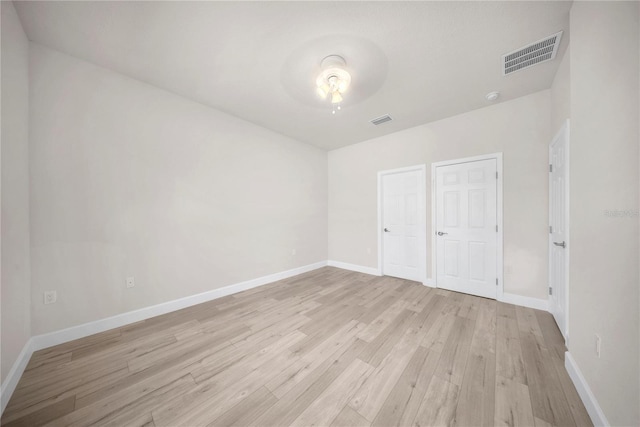 unfurnished bedroom featuring light wood-style floors, baseboards, and visible vents