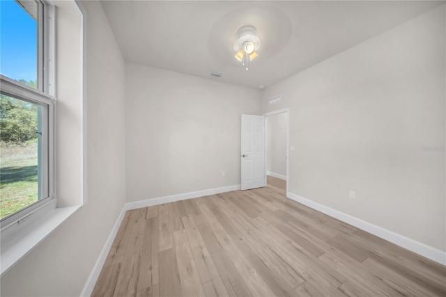 unfurnished room with a ceiling fan, light wood-type flooring, visible vents, and baseboards