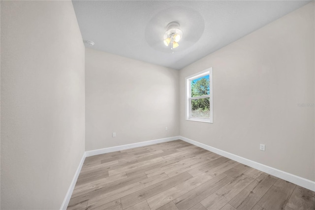 empty room featuring ceiling fan, light wood finished floors, and baseboards