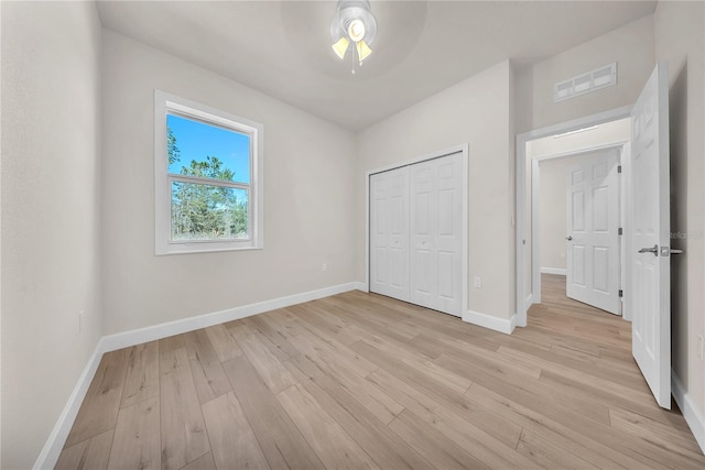 unfurnished bedroom with ceiling fan, light wood-style flooring, visible vents, baseboards, and a closet