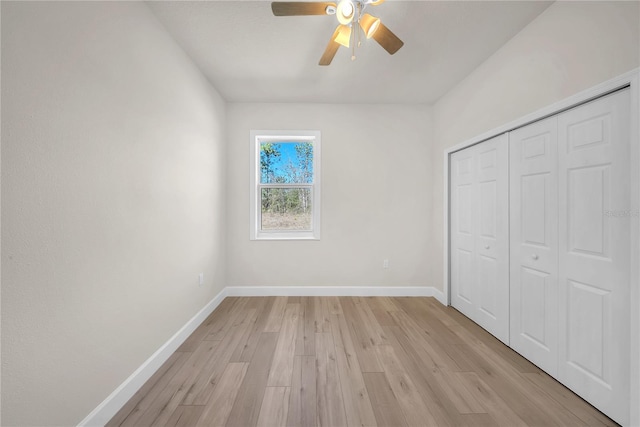 unfurnished bedroom with ceiling fan, a closet, light wood-type flooring, and baseboards