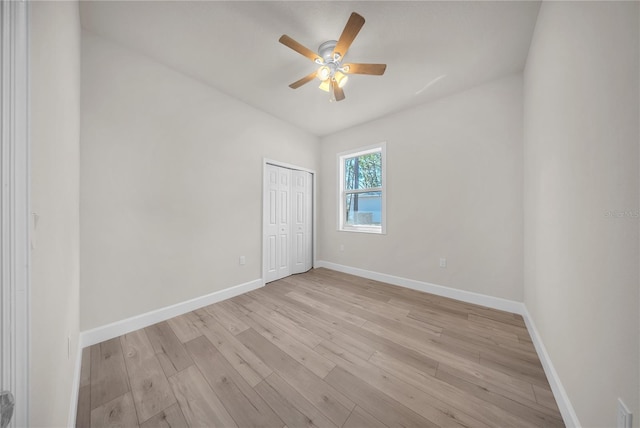 spare room featuring a ceiling fan, baseboards, and light wood finished floors