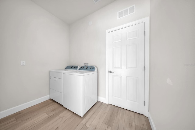 clothes washing area featuring visible vents, separate washer and dryer, light wood-type flooring, laundry area, and baseboards