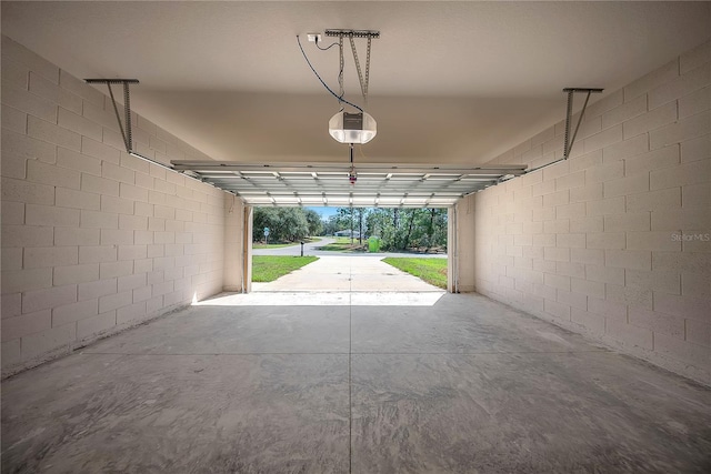 garage featuring concrete block wall and a garage door opener