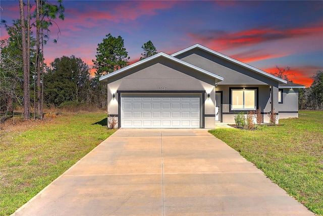 view of front of house featuring driveway, a garage, a front lawn, and stucco siding