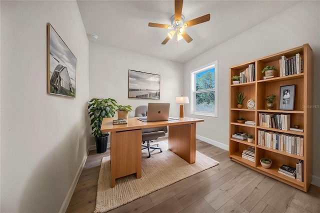 office space with light wood finished floors, a ceiling fan, and baseboards