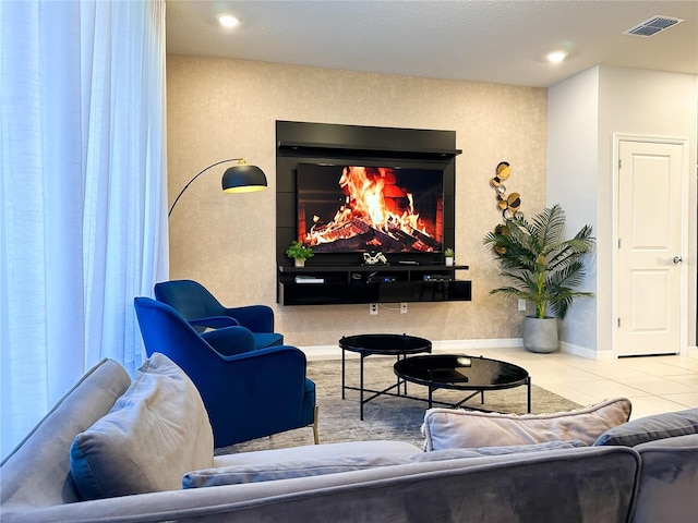 interior space featuring a glass covered fireplace, tile patterned floors, baseboards, and visible vents