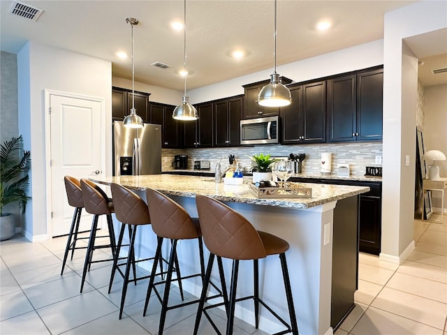 kitchen featuring visible vents, stainless steel appliances, a kitchen bar, and light stone countertops