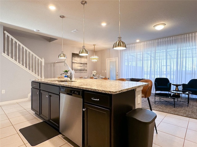 kitchen with light tile patterned floors, dishwasher, a sink, and hanging light fixtures