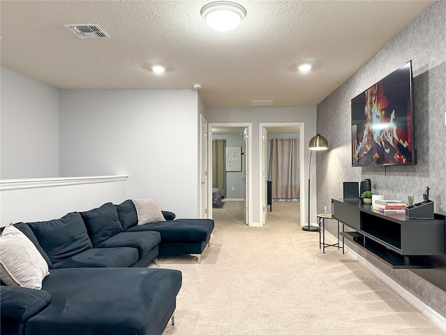 living area with a textured ceiling, baseboards, visible vents, and light carpet