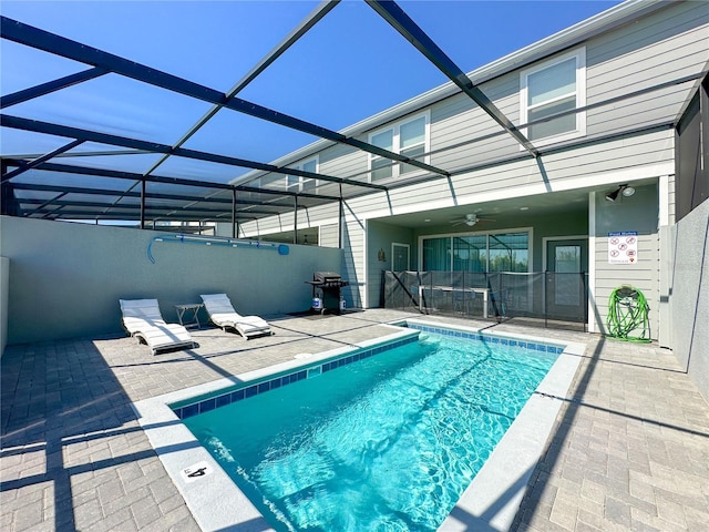 pool with glass enclosure, a patio, ceiling fan, and grilling area