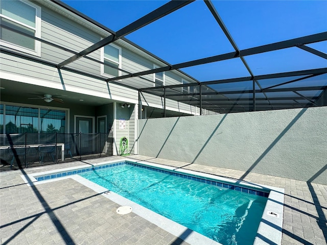 view of pool featuring glass enclosure, ceiling fan, and a patio