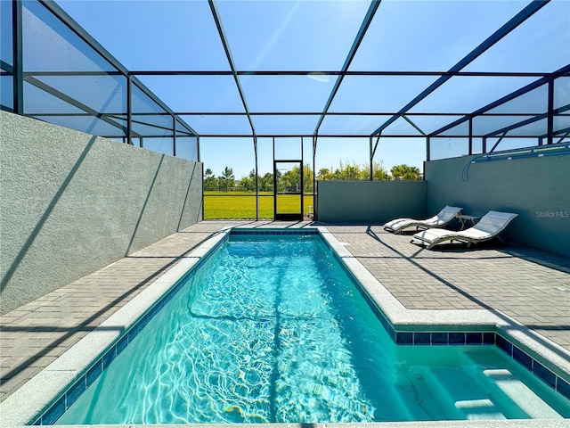 view of pool with glass enclosure and a patio