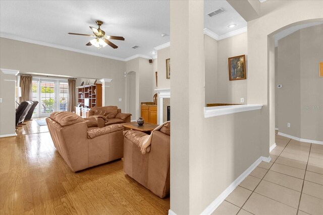 living room featuring light hardwood / wood-style flooring, ceiling fan, and crown molding