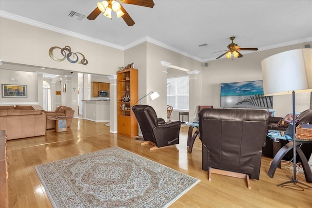 living room featuring ceiling fan, ornamental molding, and light hardwood / wood-style flooring