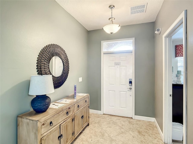 foyer entrance with a textured ceiling and light tile patterned floors