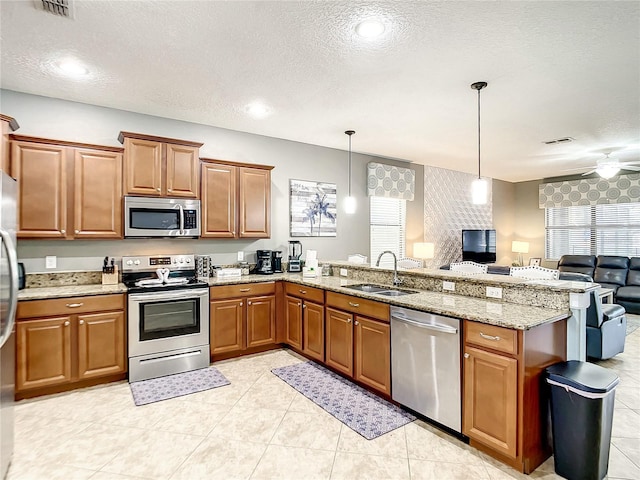 kitchen with a textured ceiling, pendant lighting, appliances with stainless steel finishes, sink, and ceiling fan