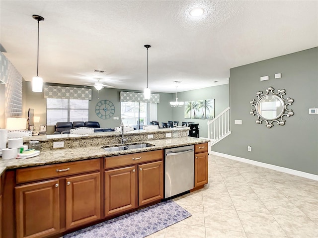 kitchen with decorative light fixtures, light stone counters, sink, stainless steel dishwasher, and a textured ceiling