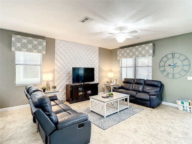 living room featuring ceiling fan and a textured ceiling