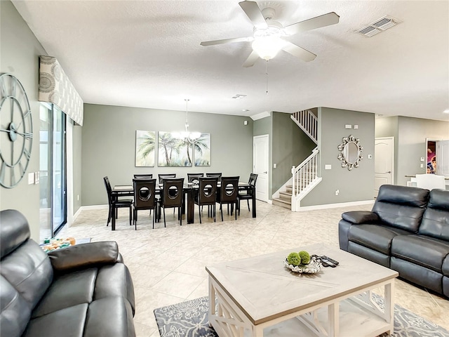 tiled living room featuring ceiling fan with notable chandelier and a textured ceiling